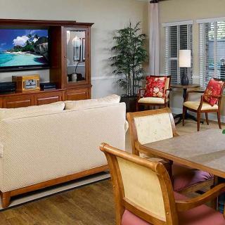 A cozy living room with a TV, sofa, dining table, and stylish wooden furniture.