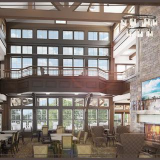 A spacious lodge interior with large windows, a cozy seating area, and a grand fireplace.