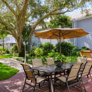 A serene outdoor seating area with a table, chairs, and umbrella set amidst lush greenery.