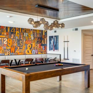 A modern game room featuring a stylish pool table, abstract artwork, and contemporary lighting.