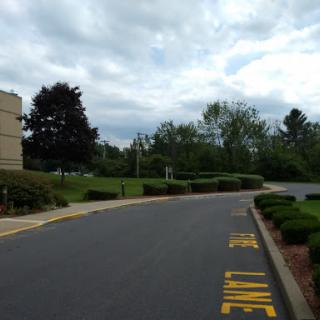 A winding road leading through a landscaped area under a cloudy sky.