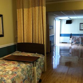 A well-lit hospital patient room featuring a bed and curtains for privacy.