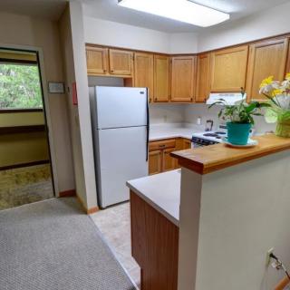 A modern apartment kitchen with wooden cabinets and stainless steel appliances.