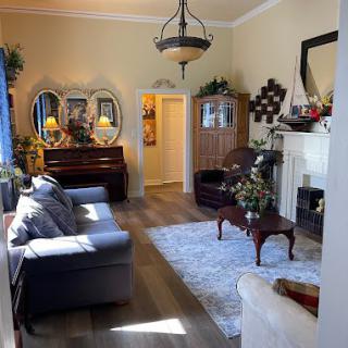 A cozy living room featuring elegant furniture, a piano, and decorative mirrors.