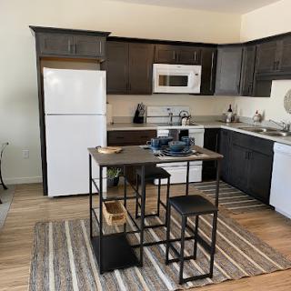 A modern kitchen featuring sleek cabinetry, essential appliances, and a cozy dining area.