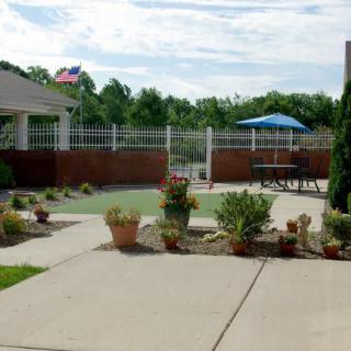 A cozy outdoor patio area with potted plants and seating under an umbrella.