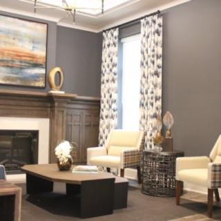 A modern living room with elegant decor, featuring two armchairs, a central coffee table, and a fireplace adorned with artwork.
