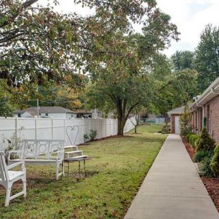 A serene garden path with chairs and trees lining a fenced area.