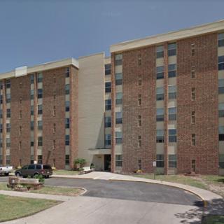 A multistory brick apartment building with several windows and a welcoming entrance.
