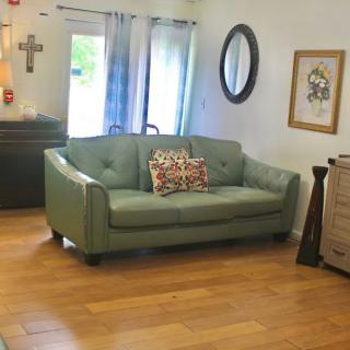 A cozy living room with a green sofa, mirror, and wooden flooring.