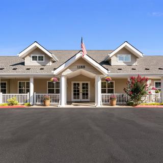 A spacious residential building with a well-maintained front yard and an American flag.