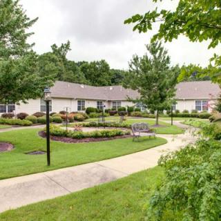 A scenic view of a well-maintained garden with a winding pathway, surrounded by houses and lush greenery.