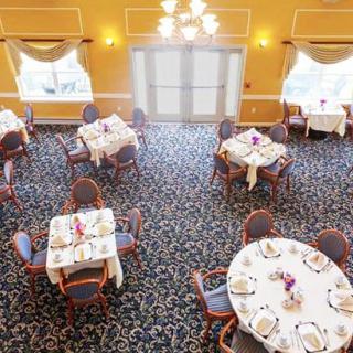 A spacious and elegantly decorated dining room with round tables set for a formal occasion.