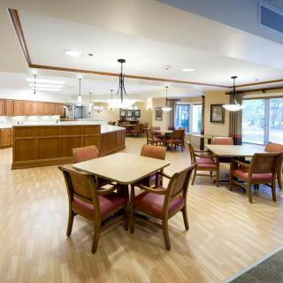 A spacious dining area with wooden tables and chairs, featuring a kitchen in the background.