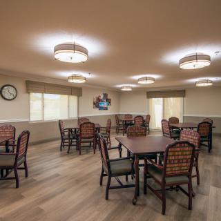 A spacious dining area with neatly arranged tables and chairs under warm, bright lighting.