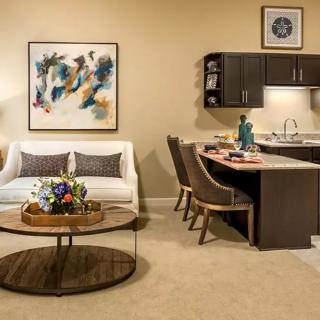 A modern living space featuring a cozy seating area with artwork and an adjacent kitchen.