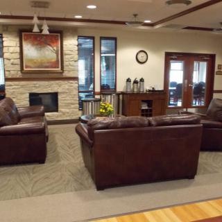A welcoming lobby with leather couches and a fireplace alongside a coffee station.