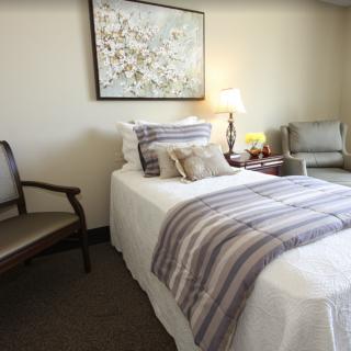 A cozy bedroom with a neatly made bed, decorative pillows, and a bedside lamp.