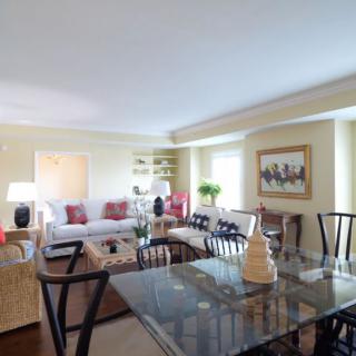 A cozy living and dining area featuring a glass table, comfortable seating, and tasteful decor.
