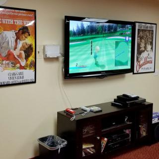 A cozy living room setup with a TV, gaming console, and movie posters on the wall.