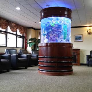 A large, cylindrical aquarium serves as a stunning centerpiece in a cozy lobby area.