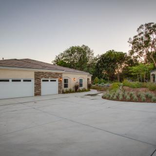 A modern house with a spacious driveway and surrounding greenery.