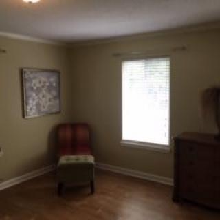 A minimalist room with a chair, window, and artwork on the wall.