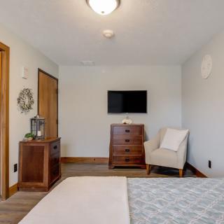 A modern and minimalist bedroom with a mounted television, dresser, and comfortable chair.