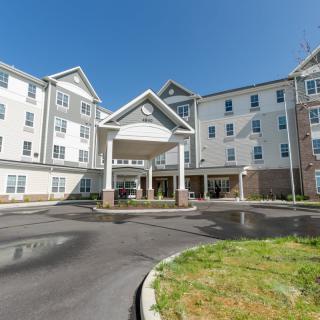 A large residential building with an entrance and parking area on a clear day.