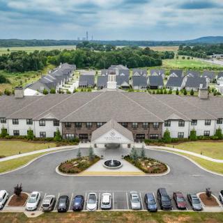Aerial view of a large residential building with a surrounding parking lot and suburban landscape.