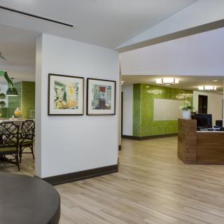 A modern lobby area with green accents, featuring a reception desk and artwork on the walls.