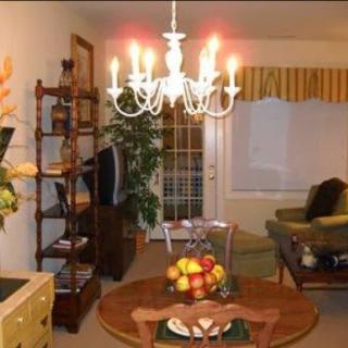 A cozy living and dining area featuring a chandelier, fruit bowl on the table, and comfortable seating.