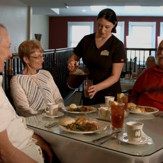 A waitress serves food to a group of people dining at a restaurant.