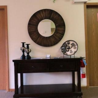 A console table with decorative items, including candlesticks and wall art, beneath a round mirror.