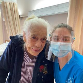 A caregiver and an elderly patient share a warm moment in a healthcare setting.