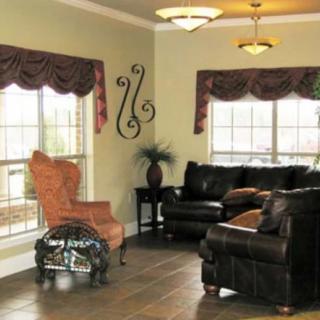 A cozy living room with sofas, a chair, large windows, and decorative elements.
