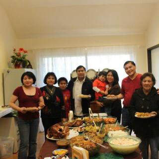 A family gathering around a dining table filled with various dishes, celebrating indoors.