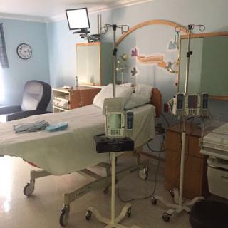A hospital patient room equipped with a bed, medical devices, and an IV stand.