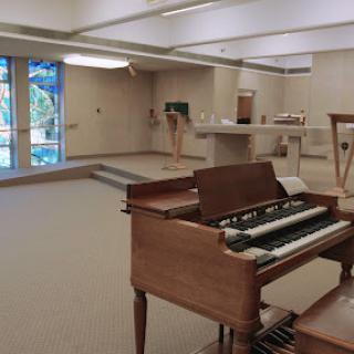 A spacious interior of a music area featuring an organ, illuminated by natural light.