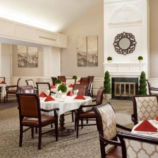 A well-decorated dining room with elegantly set tables and a cozy fireplace.