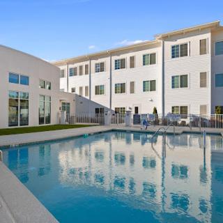 A modern apartment complex featuring a serene swimming pool surrounded by well-designed outdoor spaces.
