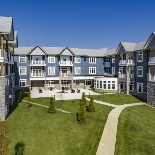 A modern residential apartment building with a well-maintained lawn and pathways.