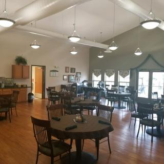 A spacious dining area with multiple tables and chairs, well-lit by overhead lights.