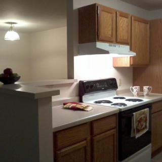 An apartment kitchen with wooden cabinets and a stove.