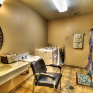 A clean bathroom with a sink, mirror, chair, and laundry appliances.