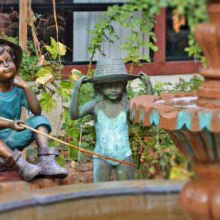 A whimsical garden sculpture featuring two children near a fountain.