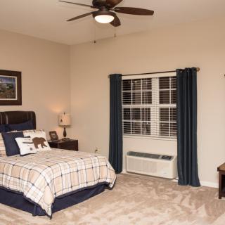 A cozy bedroom with a bed, lamp, and window curtains.
