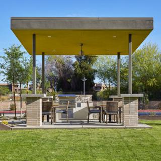 A modern outdoor gazebo with seating area and garden view.
