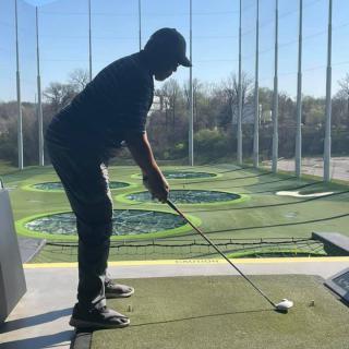 A person preparing to hit a golf ball at a driving range.