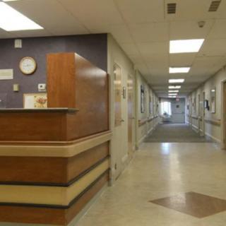 A hospital corridor with a reception desk and a long hallway.